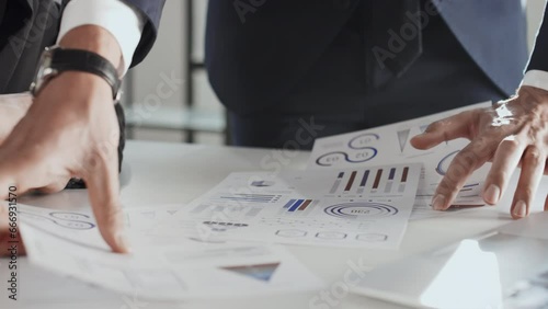 Close up midsection slowmo shot of unrecognizable businessman standing and explaining project efficiency to business associate using charts in documents during office meeting