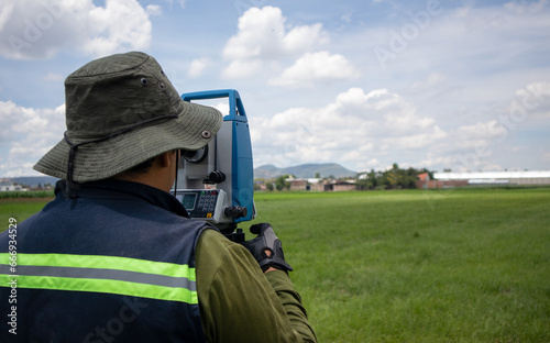 unrecognizable hispanic land surveyor engineer measuring a field using a theodolite surveying equipment; survey instrument being used by a professional working with a total station
