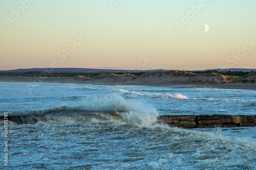 Storm hitting the coast of Scotland with crashing waves coming over a harbour wall