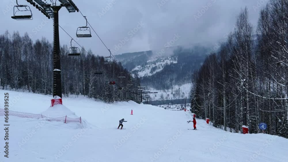 A chairlift at a ski resort on a cloudy winter day in the Ural Mountains. A lift on the background of factory pipes. Climbing the mountain. Gubakha, Perm Krai, 4K A chairlift at a ski resort on a cloudy winter day in the Ural Mountains. A lift on the background of factory pipes. Climbing the mountain. Gubakha, Perm Krai, 4K