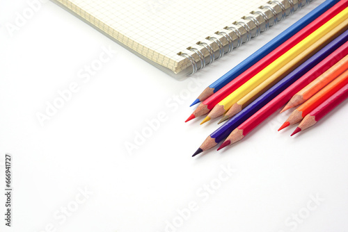 Focus of colored pencils or pastel lined up and blur graph book on white background. Learning, study and presentation concept.