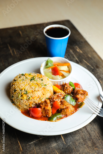Chili Chicken Rice Meal served in plate with sauce, cold drink, spoon and fork isolated on wooden board side view of thai food