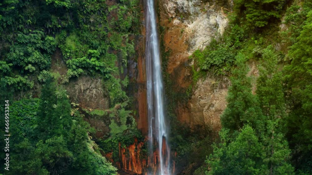 Cinematic Aerial Drone shot of Ribeira Quente natural waterfall in Sao Miguel in the Azores - Portugal.
View of lush green tropical forest surrounding the waterfall.
Top Down camera rising up.