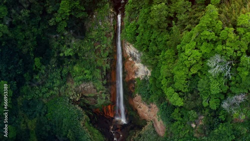 Cinematic Aerial Drone shot of Ribeira Quente natural waterfall in Sao Miguel in the Azores - Portugal.
View of lush green tropical forest surrounding the waterfall.
Camera circling around the stream photo