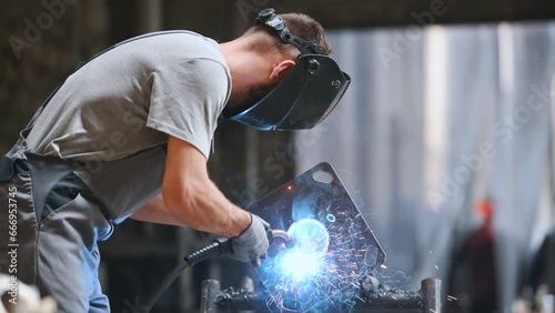 The welder works at the factory collects a metal part. Working with Steel industry photo