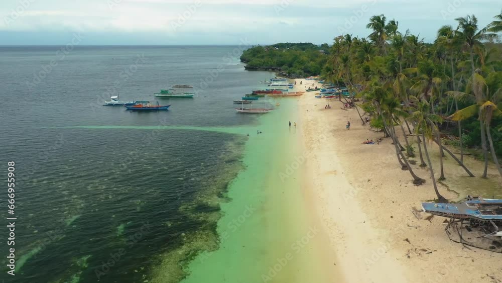 Tubod beach, Siquijor Island, Philippines. Aerial drone view. Tourists and locals swimming and enjoying the summer sun. Colorful boats in clear turquoise water. Tubod beach, Siquijor Island, Philippines. Aerial drone view. Tourists and locals swimming and enjoying the summer sun. Colorful boats in clear turquoise water.