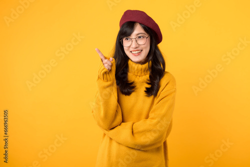 A pensive woman in her 30s, wearing a red beret and eyeglasses, contemplating against a vibrant yellow background. © Jirawatfoto