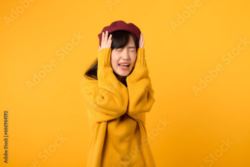 Amidst the noise, a stylish Asian lady, dressed in a yellow sweater and red beret, listens attentively against a vibrant yellow setting.