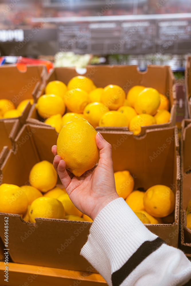 hand taking lemon from grocery store shelf