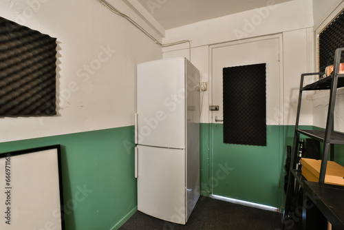 a green and white room with two refrigerators, one on the wall and another on the floor in the corner