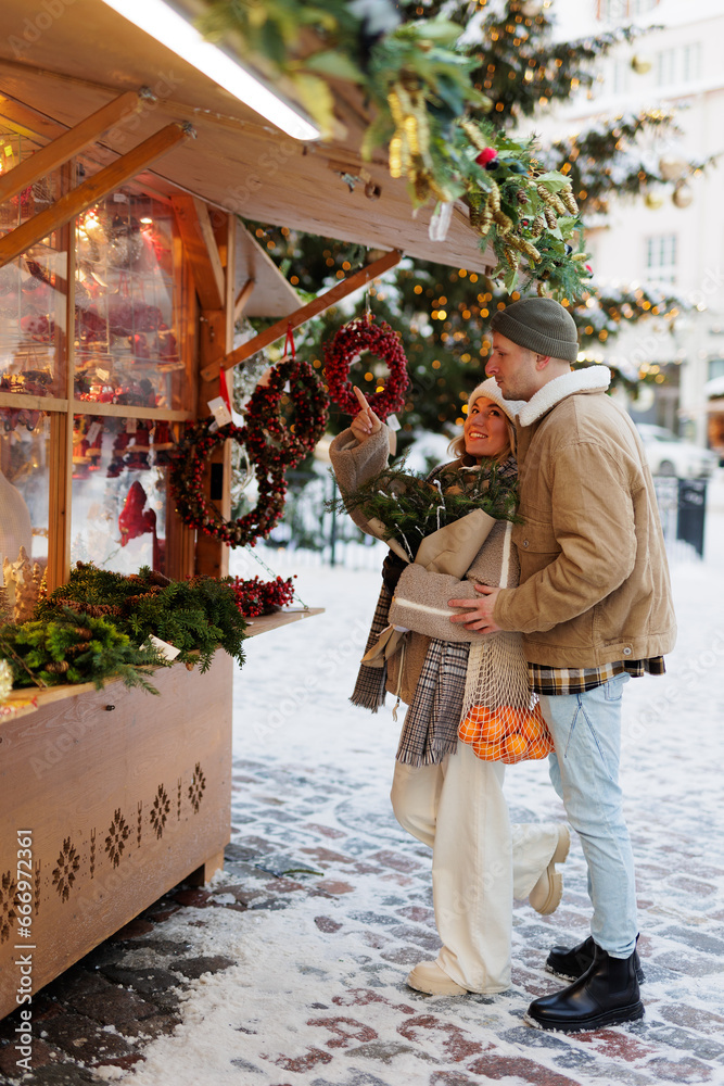 Happy couple at the christmas market choosing something in shop
