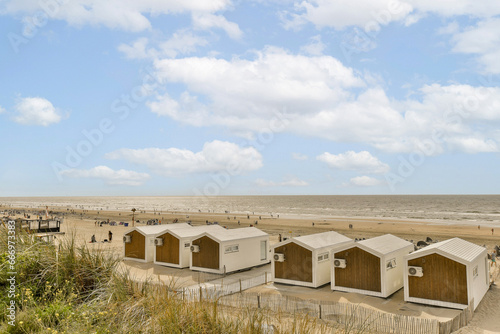 Wallpaper Mural some beach huts on the sand dunes in front of an ocean and blue sky with white puffy clouds above Torontodigital.ca