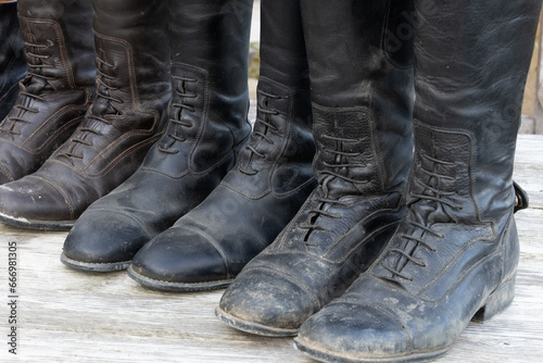 schmutzige alte Reitstiefel Leder bereit zur Reinigung aufgereiht auf einem alten Holztisch