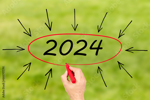 2024, Woman writing the number 2024 on green background. Happy New Year