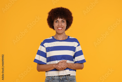 Portrait of happy young woman on orange background