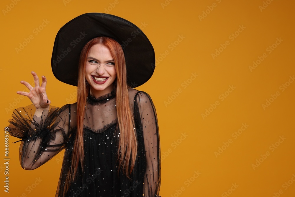 Happy young woman in scary witch costume on orange background, space for text. Halloween celebration Happy young woman in scary witch costume on orange background, space for text. Halloween celebration