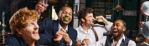 banner of four happy and drunk multiethnic friends in formal wear drinking tequila in bar after work