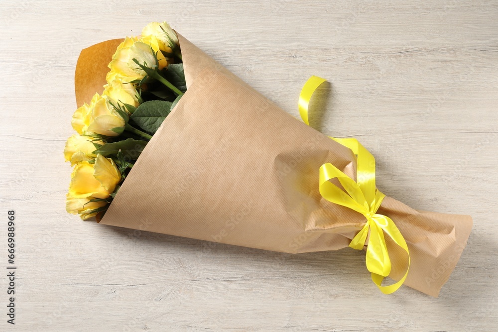 Beautiful bouquet of yellow roses with ribbon on wooden table, top view - obrazy, fototapety, plakaty 