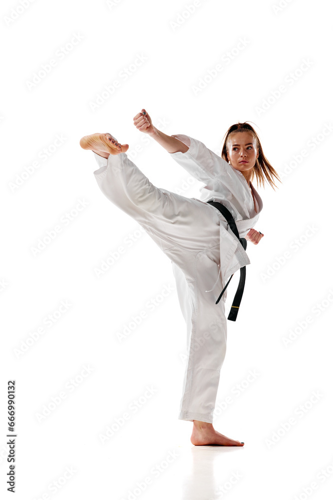 Young woman in white uniform training martial arts in action isolated over white studio background. Young woman in white uniform training martial arts in action isolated over white studio background.
