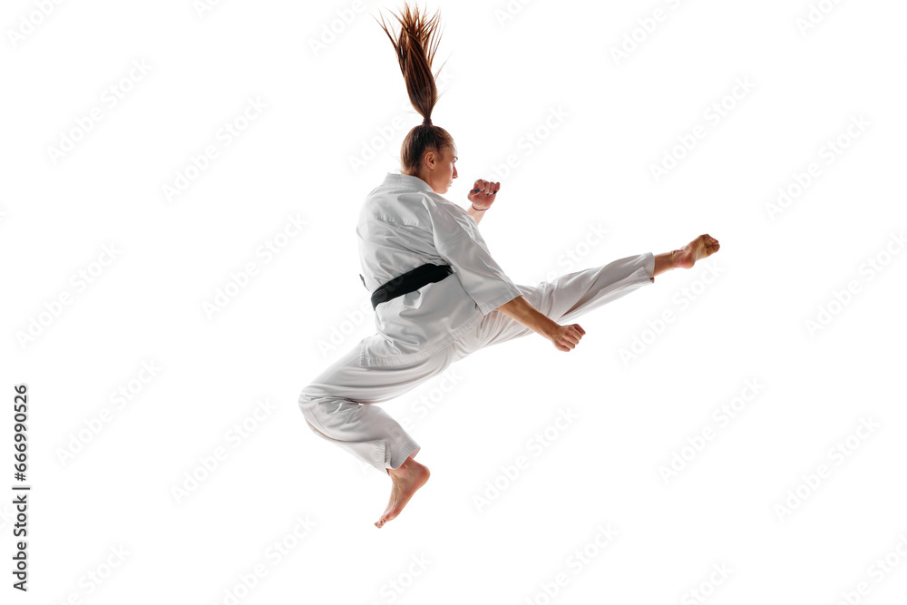 Rear view. Woman professional karate fighter jumping, training martial arts in action isolated over white background.