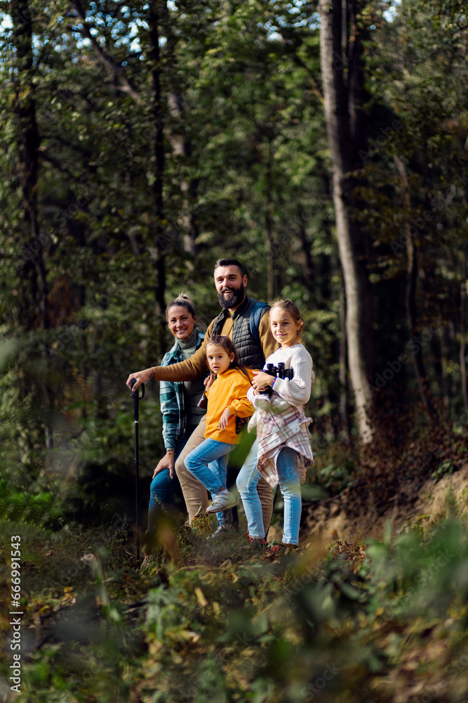 Portrait of smiling family of four exploring nature on a scenic forest hike.