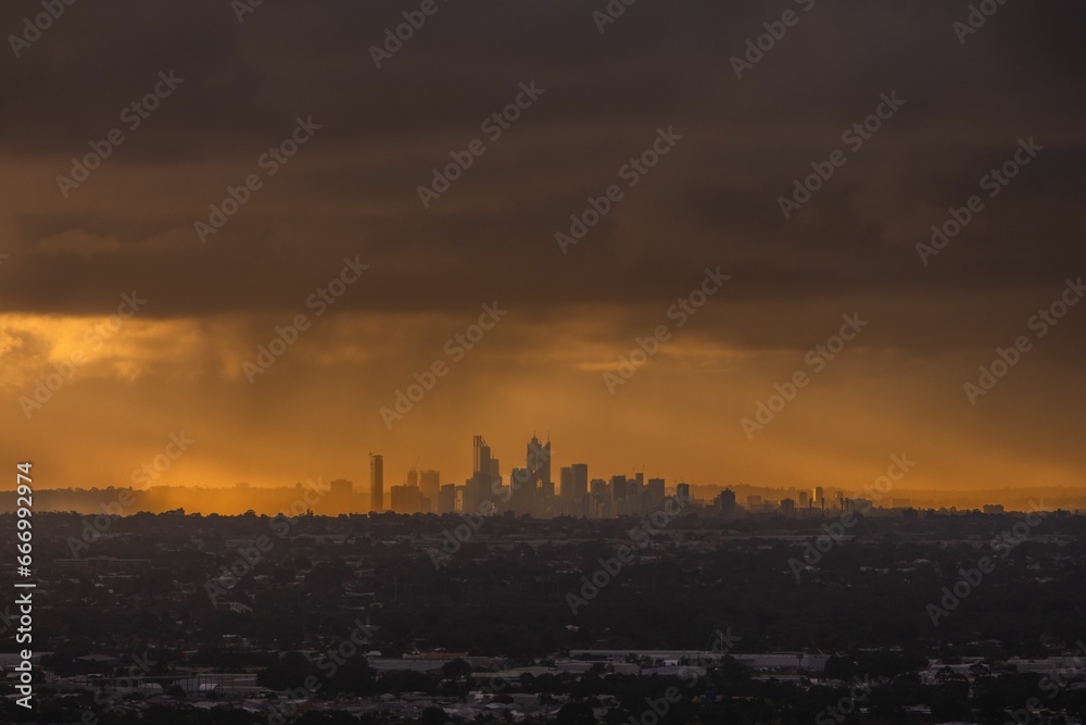 Scenic view of a city skyline at dusk, illuminated by the setting sun on a rainy day