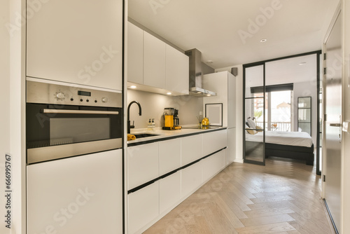 a modern kitchen with white cabinets and black appliances on the counter tops  in an open space that has wood flooring