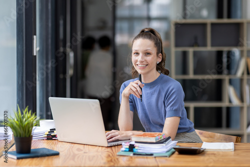 Image of young beautiful joyful Canada woman smiling while working with laptop in office