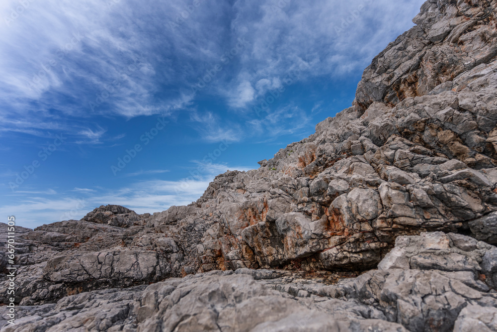 Gray stone rocks against a blue sky with clouds, nature background