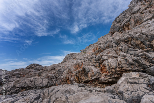 Gray stone rocks against a blue sky with clouds, nature background