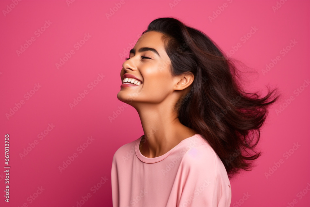 Side view of an attractive hispanic woman feeling happy in front of a bright pink background Side view of an attractive hispanic woman feeling happy in front of a bright pink background