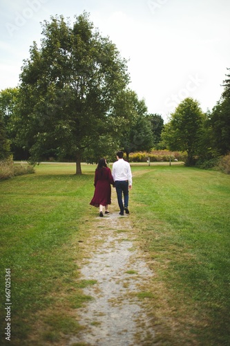the man and woman are walking in the park with one another © Wirestock
