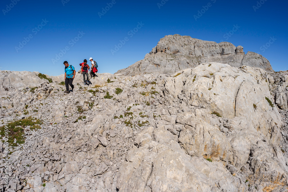 hiker advancing through the limestone relief of the Arres de Anie, Anie peak, Larra limestone plateau, Navarrese-French Pyrenees, Navarra, Spain