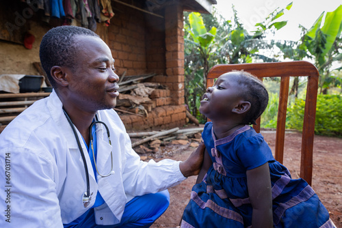 African doctor talking to a sick baby girl during a visit in a rural area in Africa photo