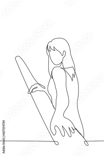 woman walks along the stairs, turning towards the viewer with both hands on one railing - one line art vector. concept model posing, captivating