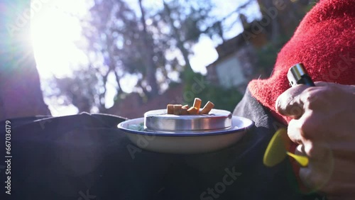 Old woman putting out her cigarette in an ashtray full of cigars