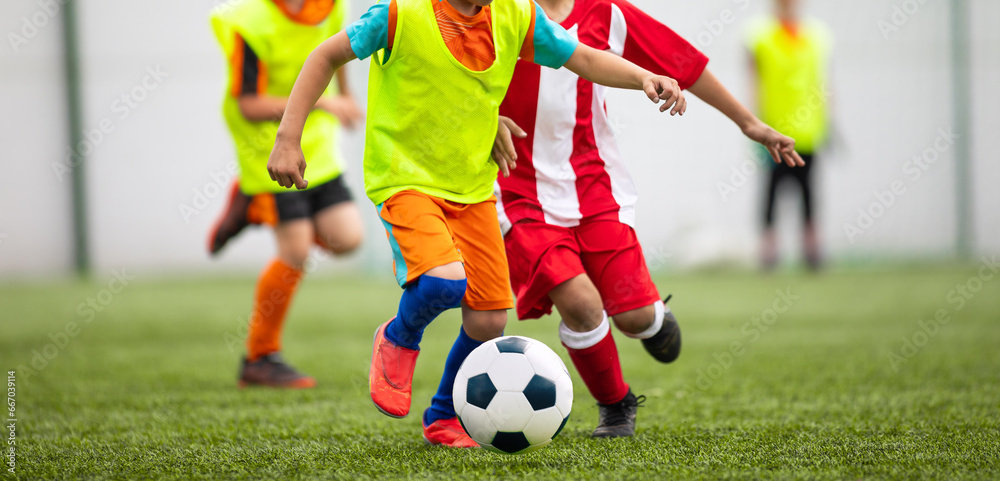 Fototapeta premium Football soccer match for children. Kids in opposite teams playing soccer game in summer tournament. School Soccer football league
