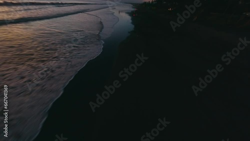 Aerial view man motorcyclist riding empty night sunset beach sea tropical landscape. FPV sport drone low cinematic shot evening dusk coast flying over endless tide calm foam wave ocean water surface