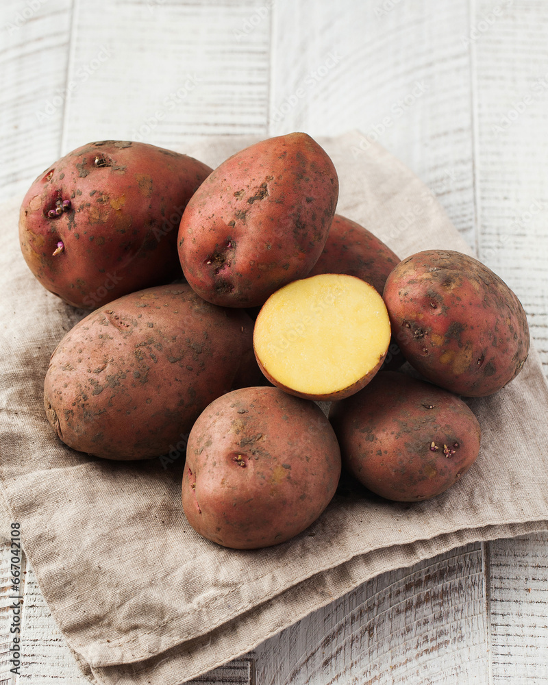 Dirty raw potatoes on a white wooden background. Vegetables, harvesting. Dirty raw potatoes on a white wooden background. Vegetables, harvesting.
