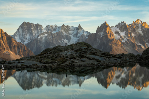 Silhouette of Hiker, Mountains and Reflection in Lac Blanc Lake at Sunset. Golden Hour. French Alps, France