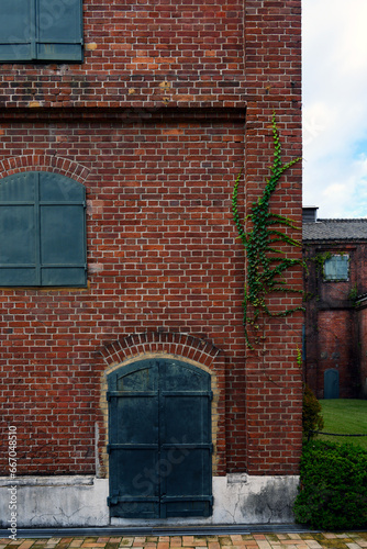 茶色いレンガ作りの古い工場の壁にある鉄製の扉と窓
