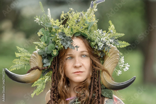 A pretty young faun in the woods. Mythological forest creature at the tree