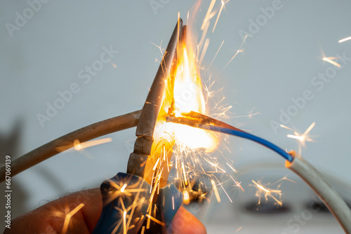 flame and sparks with pliers cutting  electrical cables, fire hazard concept, soft focus close up