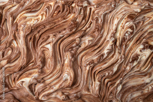 White and brown chocolate cream swirls on a birthday cake, top view abstract close up