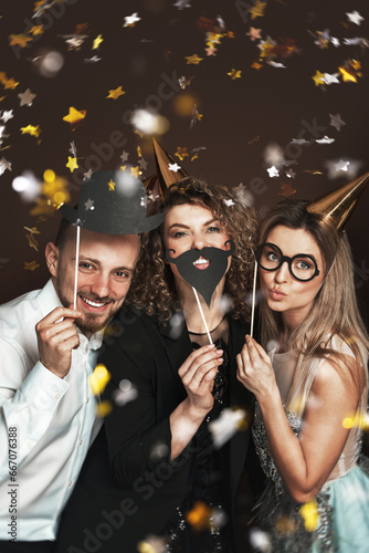 Group of happy people wearing party hats and using funny photo booth props are celebrating a holiday or event