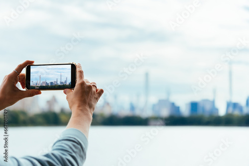 A person takes a mobile photo of the Central park pond in New York, USA.