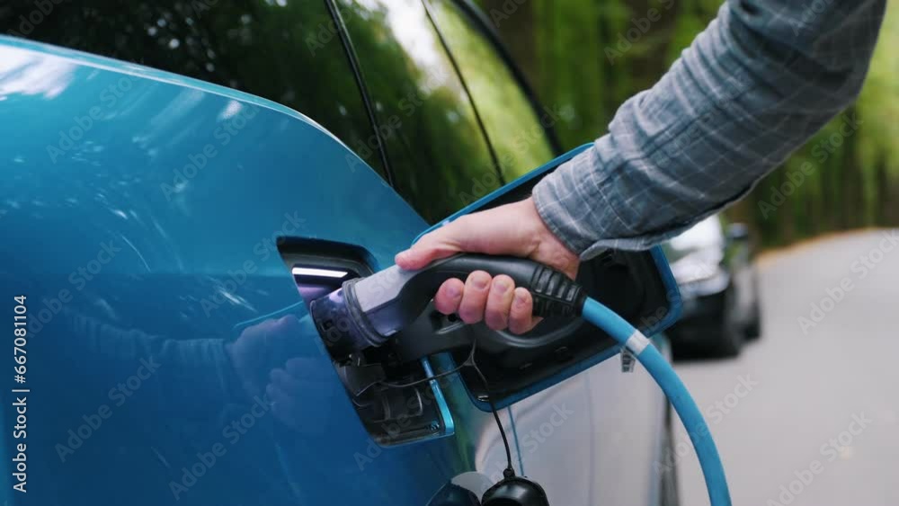 Close up Man plugging an electric car or EV at charging station at green. Save ecology alternative energy sustainable of future. Close up Man plugging an electric car or EV at charging station at green. Save ecology alternative energy sustainable of future.
