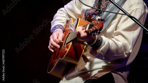 man playing an acoustic guitar in front of a microphone