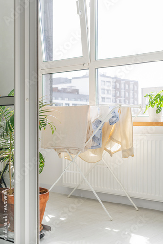 beige clothes to dry on a white clothes dryer on a bright Scandinavian balcony on a sunny day among greenery