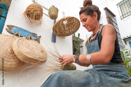 Side view of Hispanic woman weaving a basket with esparto fibers. Manual work, tradition and culture. photo